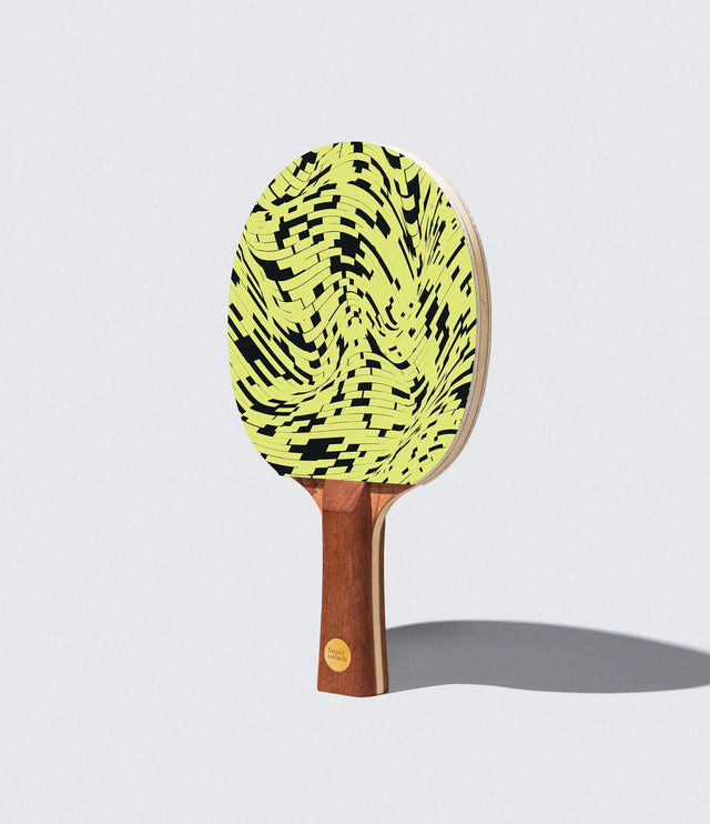 Ping pong paddle with a yellow and black pattern on a light gray background