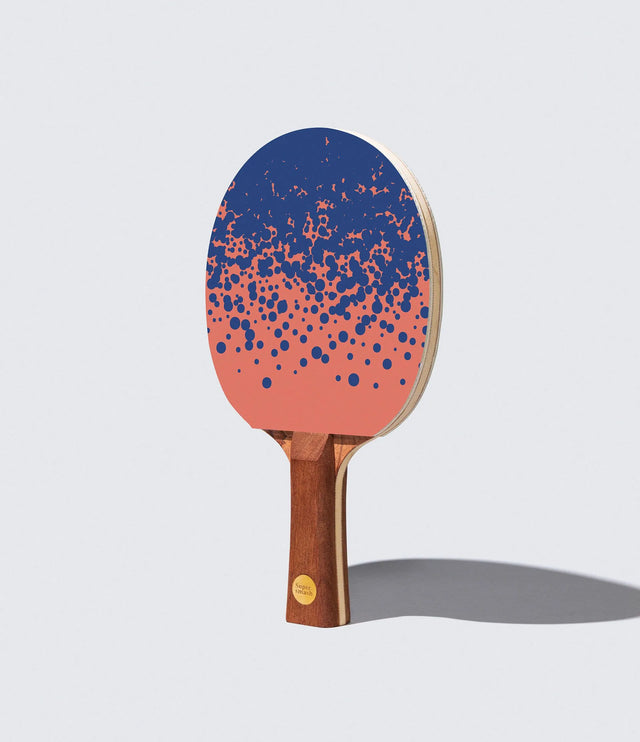 Table tennis paddle with blue and pink design on a light gray background