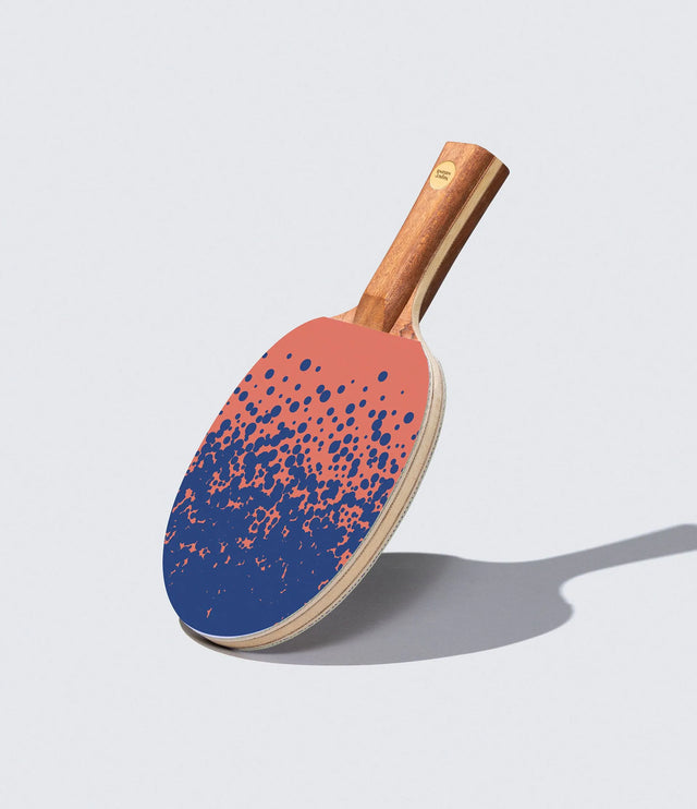 Ping pong paddle with blue and pink design on a light gray background