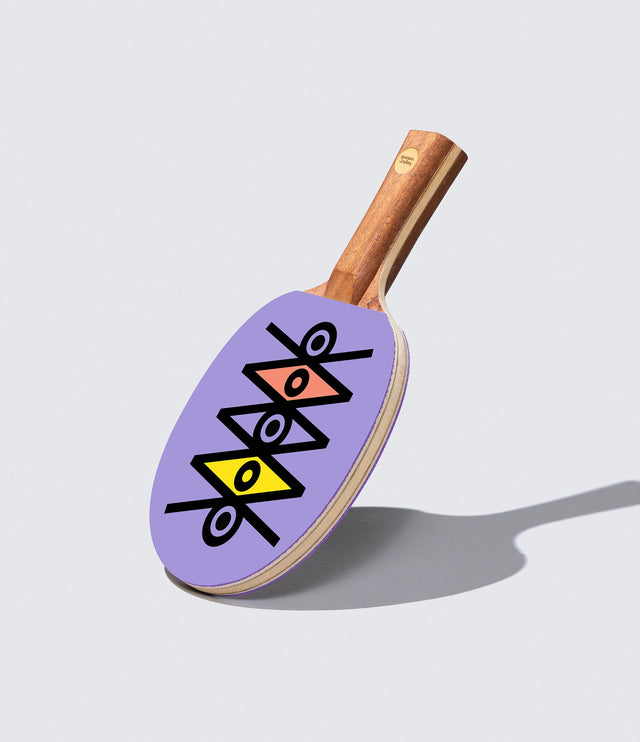 A ping pong paddle with a purple design with a natural wood handle.